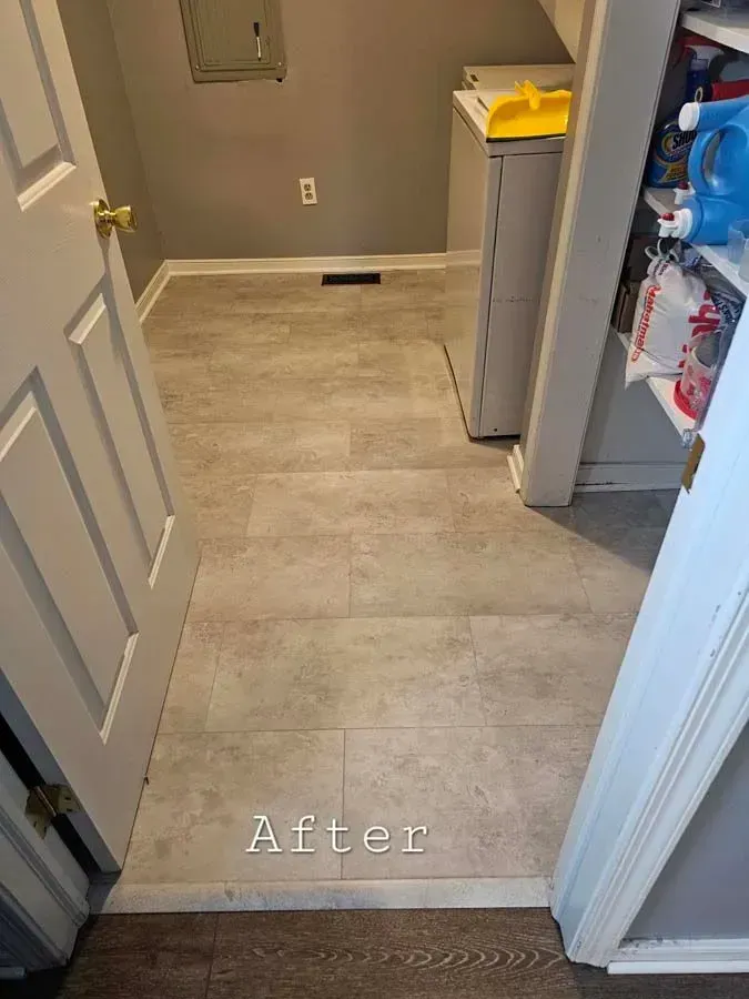 After: Laundry room with new beige tile flooring. Door on left, appliances on right.