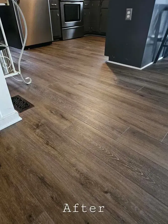 Dark brown wood-look flooring installed in a kitchen. The floor extends into the area in front of the stainless steel oven.