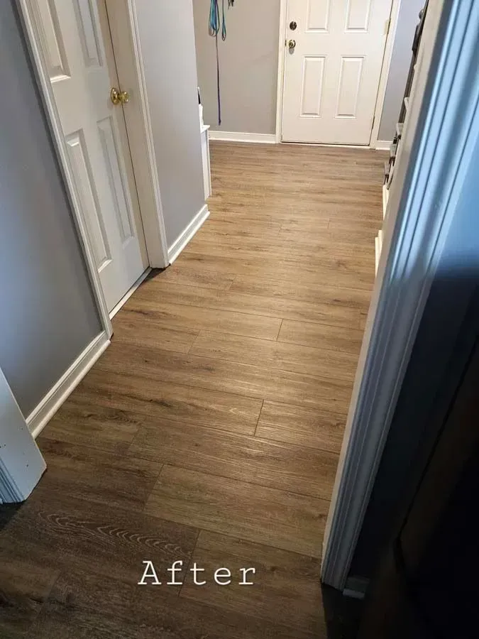 Hallway with wood-look flooring, gray walls, white trim and doors. 