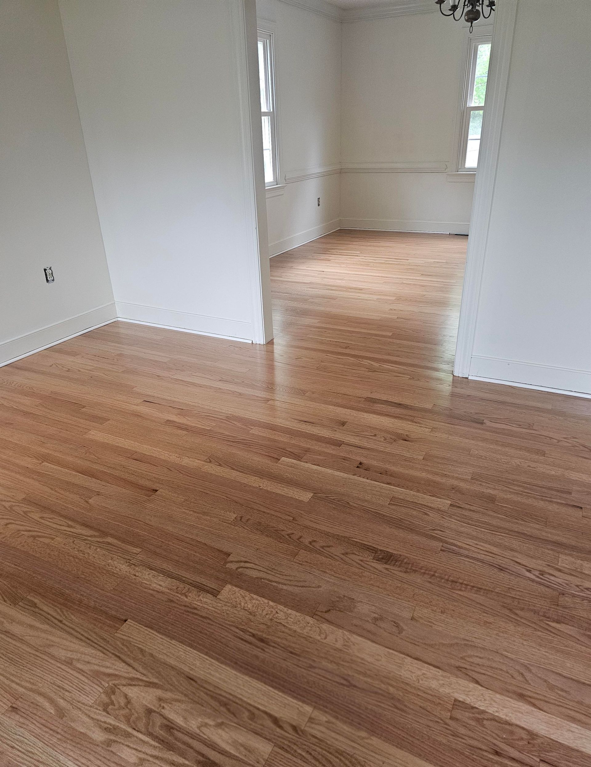 Hardwood floor in a home's entryway.  Staircase on the right and living room with furniture in the background.