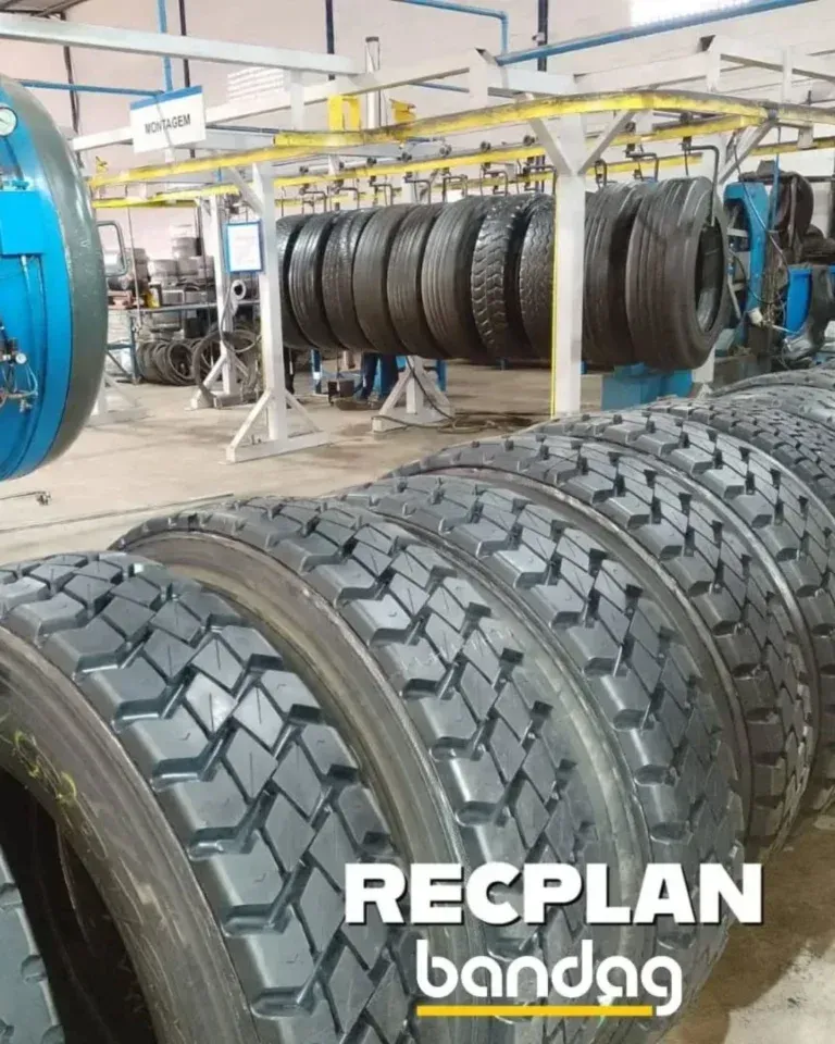 Pneus enfileirados em uma fábrica. Alguns em um sistema de esteiras, outros em fila. Texto: RECPLAN bandag.