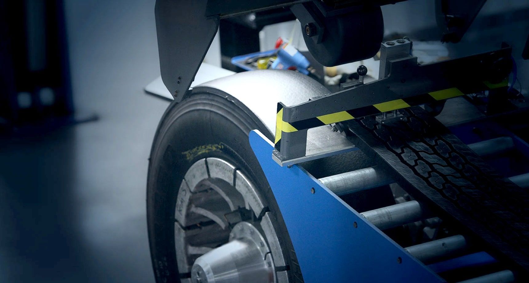 Carro cinza escuro com um pneu grande à direita, anunciando pneus.