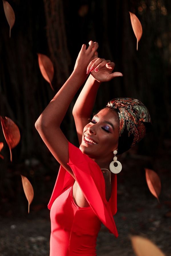 A woman in a red dress is throwing leaves in the air.