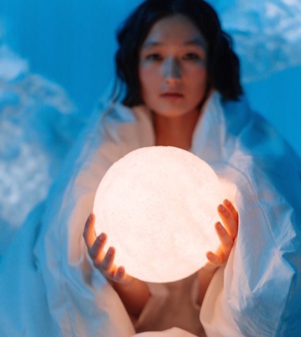 A woman is holding a light in her hands.