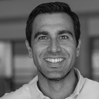 A man in a suit and plaid shirt is smiling for the camera.