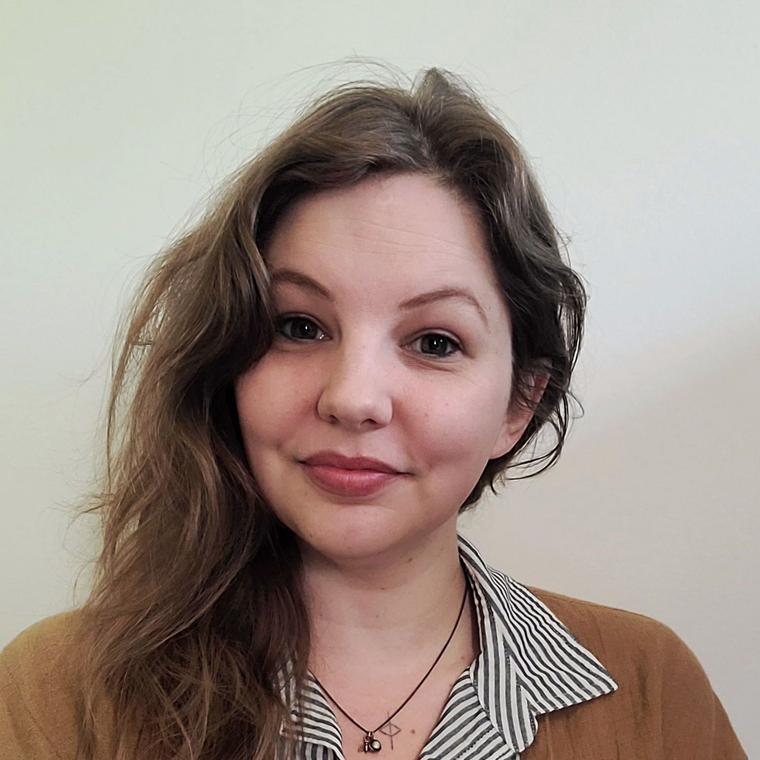 A woman wearing a striped shirt and a necklace is smiling for the camera.