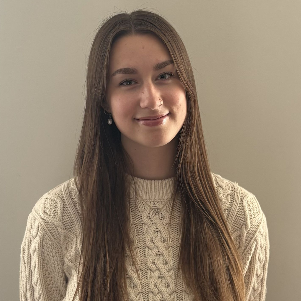 A woman wearing a knit sweater is smiling for the camera.