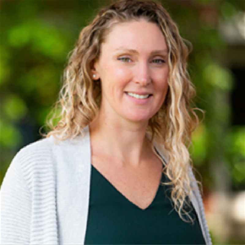 A woman with blonde hair and a green shirt is smiling for the camera.