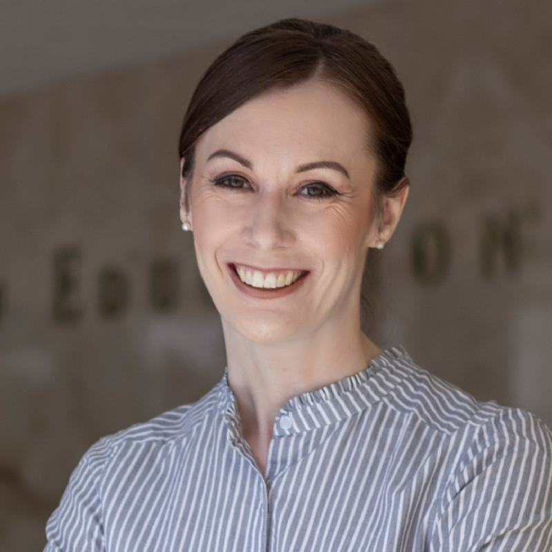 A woman in a striped shirt is smiling for the camera