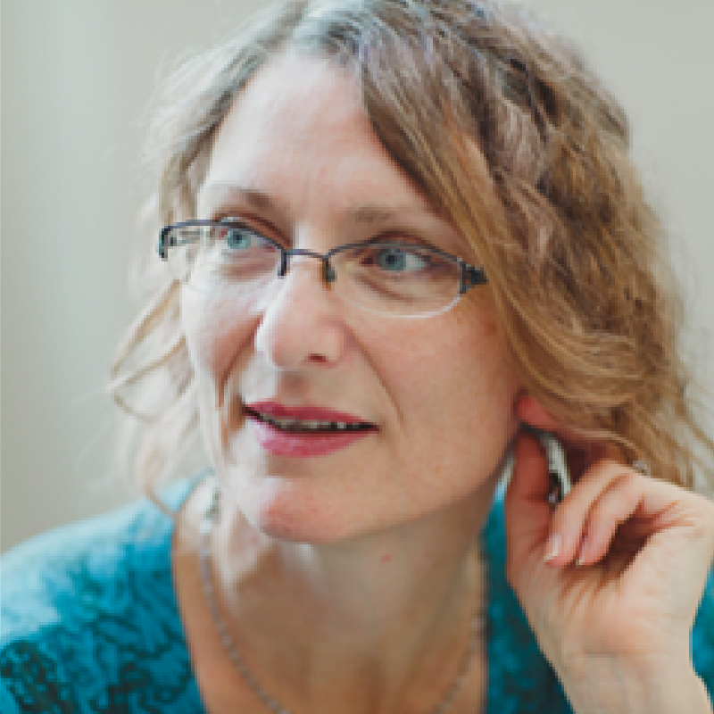 A close up of a woman wearing glasses and a blue shirt