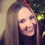 A woman with long hair is smiling in front of a christmas tree.