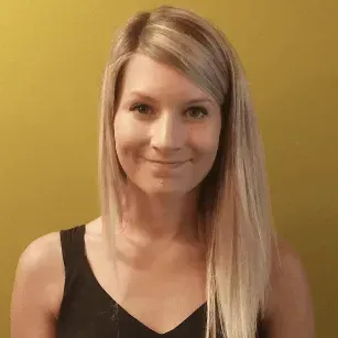 A woman with long blonde hair is smiling and wearing a black tank top.