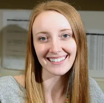 A woman with long red hair is smiling for the camera.