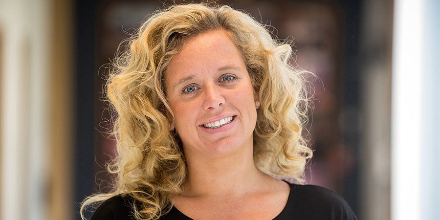A woman with blonde curly hair is smiling for the camera