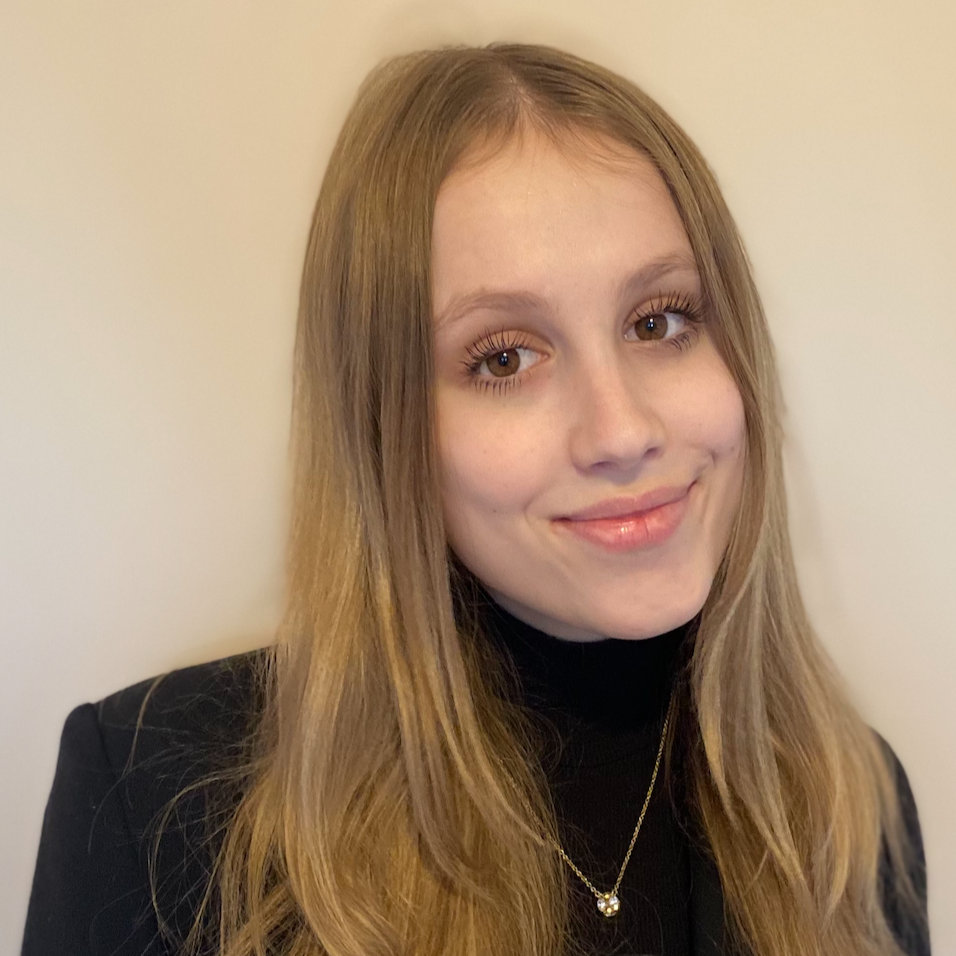 A woman wearing a black shirt and necklace is smiling for the camera.