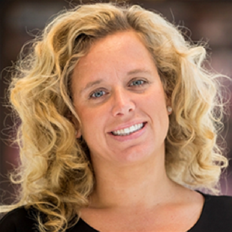 A woman with blonde curly hair is smiling for the camera