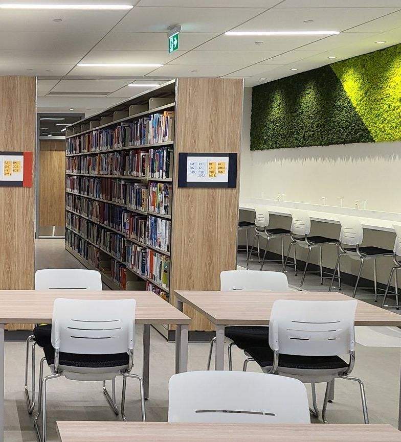 A library with tables and chairs and a green wall