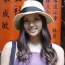 A woman wearing a hat and a purple shirt is smiling.