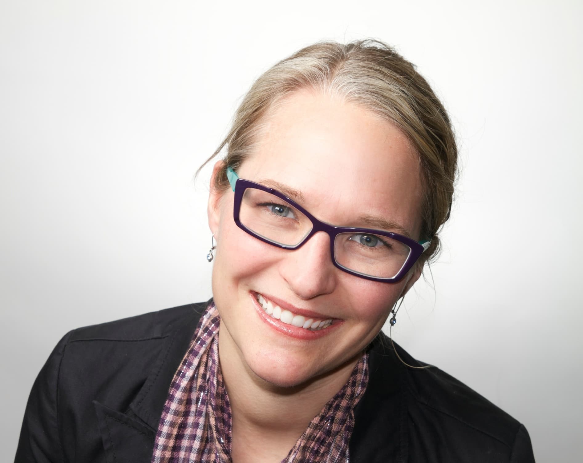 A woman with blonde hair and a blue button up shirt is smiling