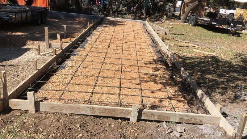 A concrete driveway is being built in a yard.