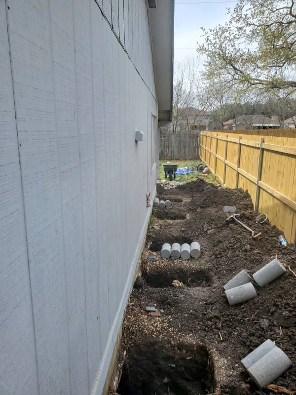 A white house with a yellow fence in the background is being remodeled.