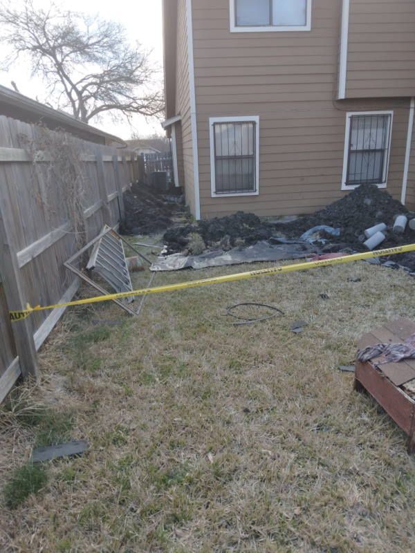 A backyard of a house with a fence and a yellow tape.