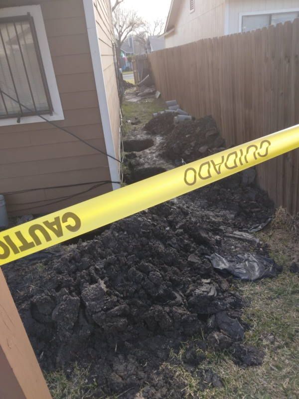 A yellow caution tape is hanging over a pile of dirt