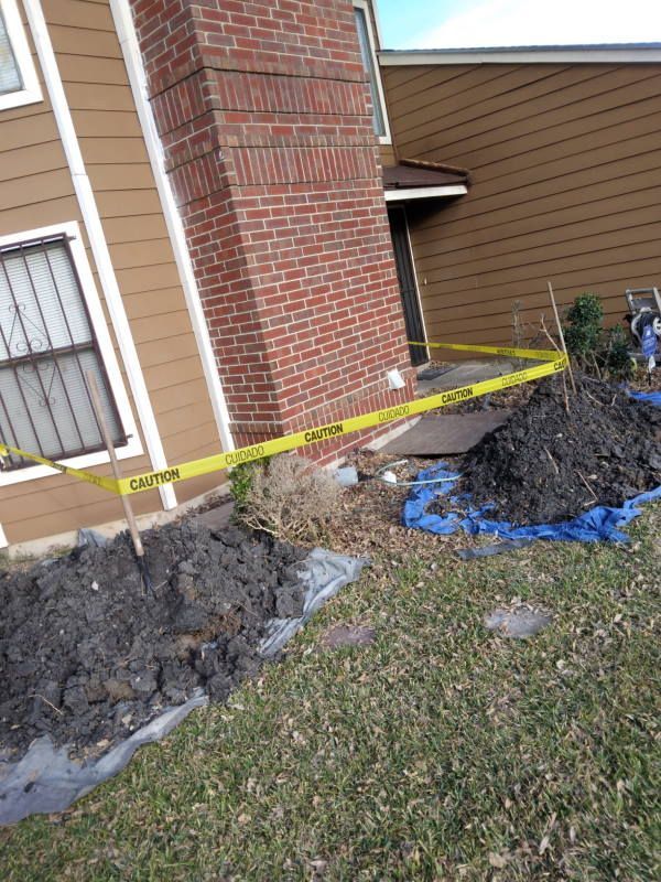 A large pile of dirt is sitting in front of a brick building.