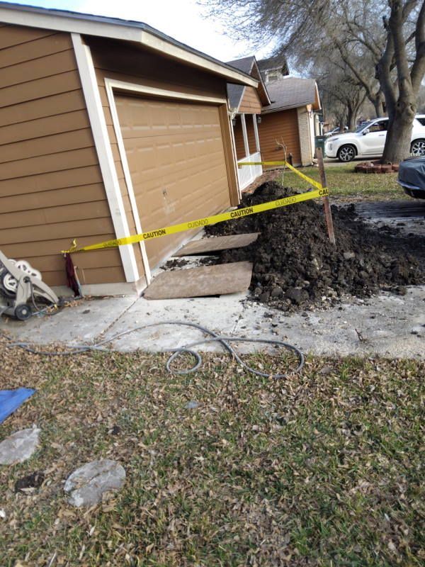 A house with a garage and a pile of dirt in front of it.