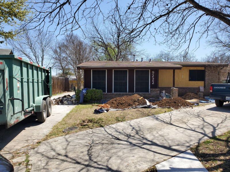 A dumpster is parked in front of a house.