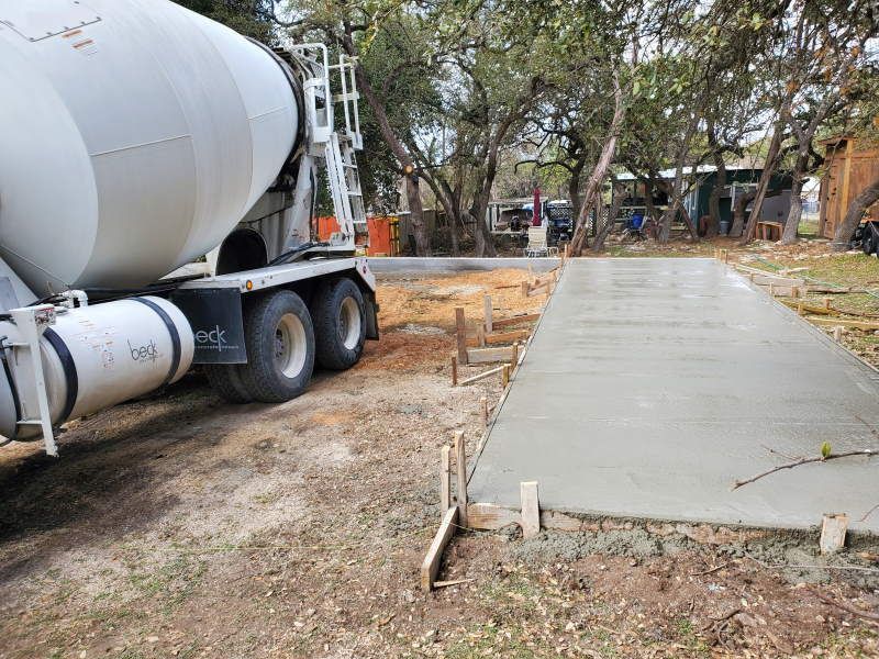 A concrete mixer truck is pouring concrete into a concrete driveway.