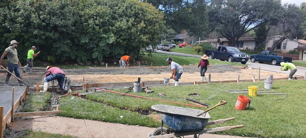 A group of construction workers are working on a concrete driveway.