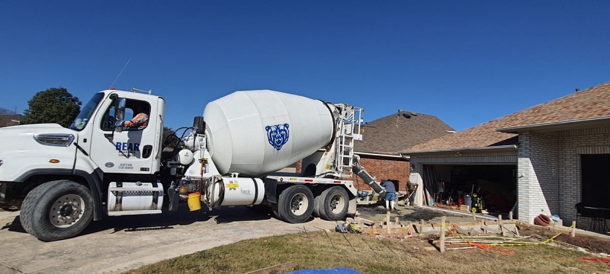 A concrete mixer truck is parked in front of a house.