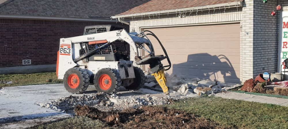 A bobcat is digging a hole in the ground in front of a house.