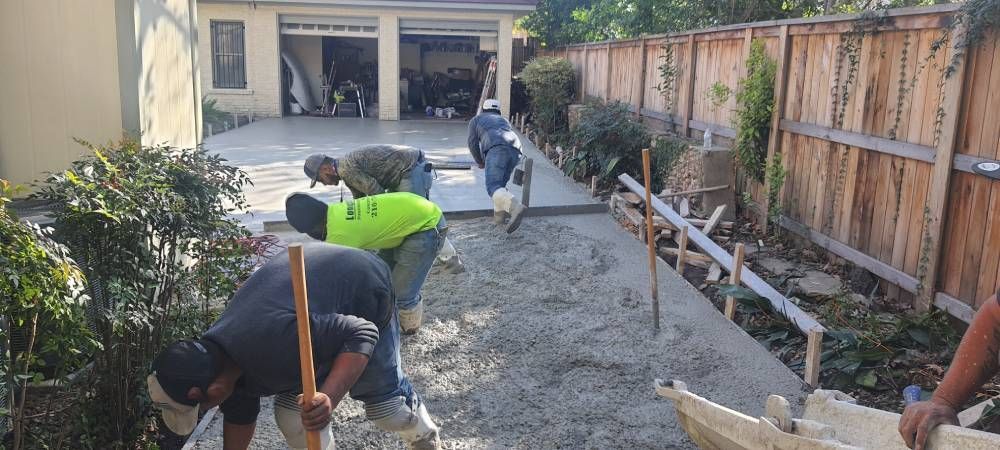 A group of men are working on a driveway in front of a house.