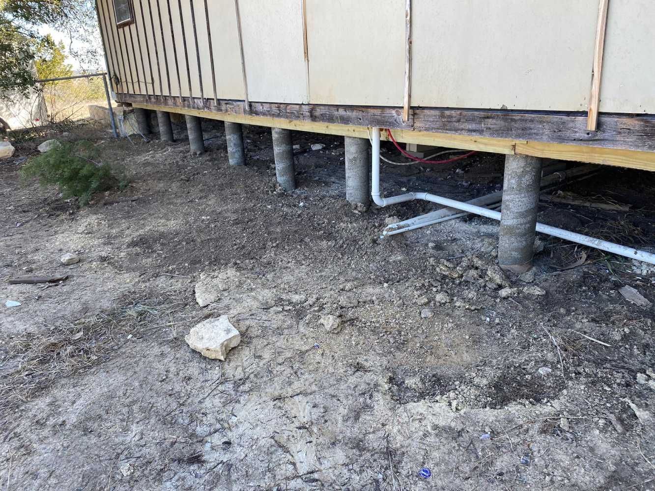 A house is being built on stilts in the dirt.