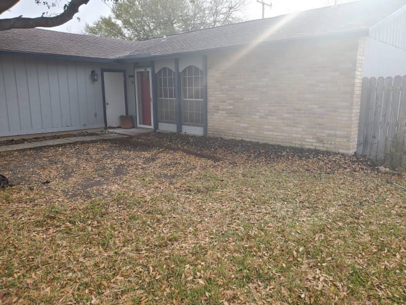 A house with a lot of leaves on the ground in front of it