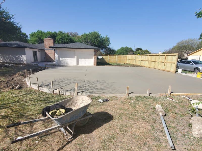 A wheelbarrow is sitting in the grass in front of a house.