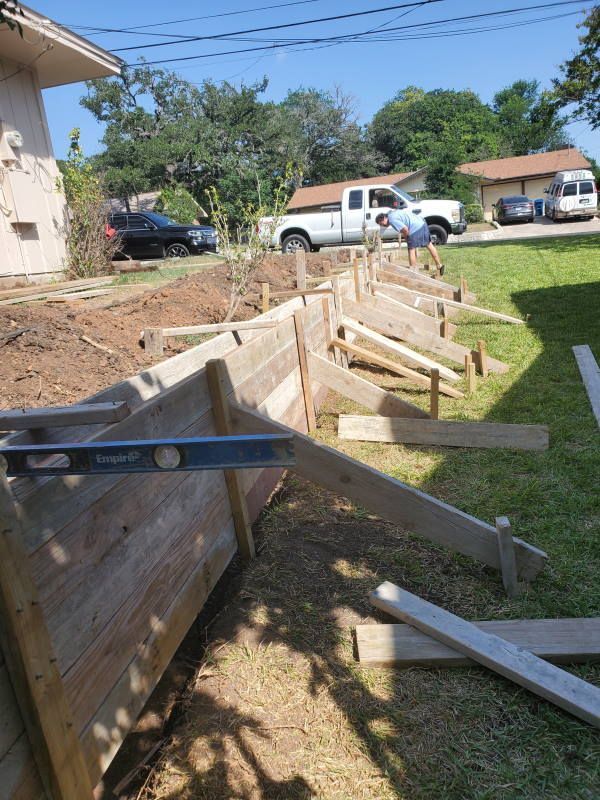 A wooden fence is being built in the backyard of a house.