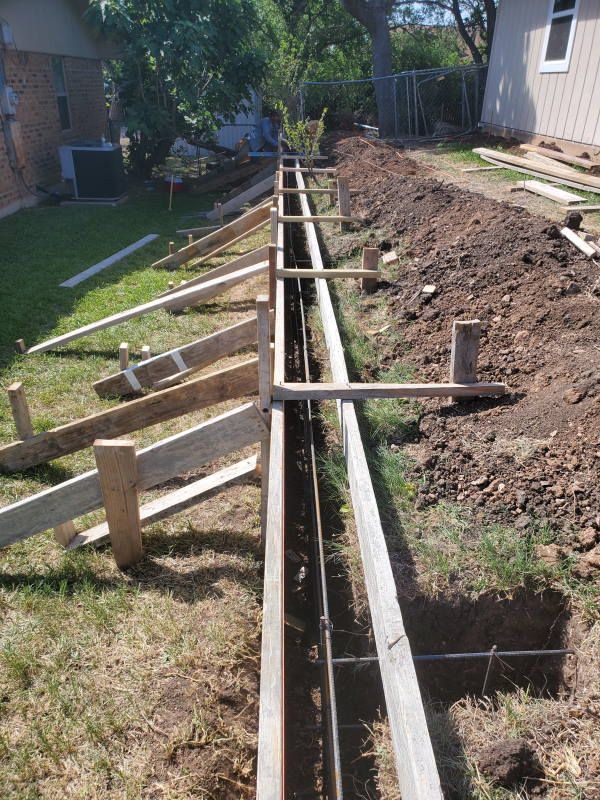 A concrete fence is being built in the backyard of a house.