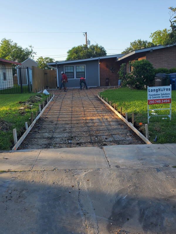 A concrete driveway is being built in front of a house.