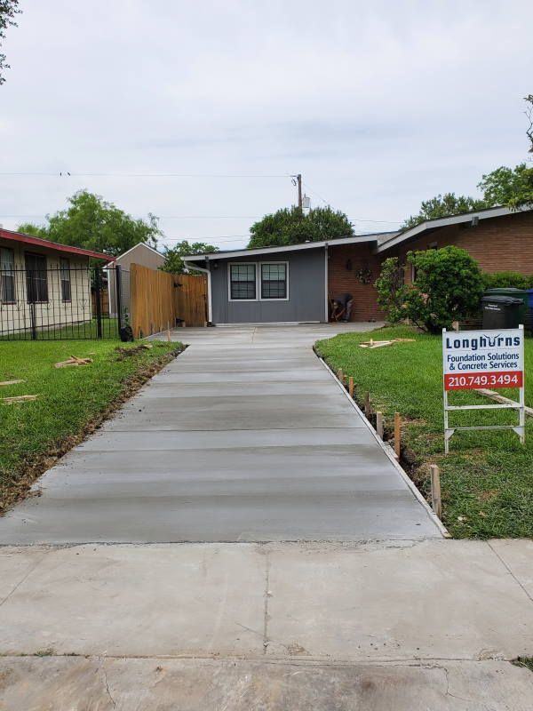 A concrete driveway is being built in front of a house.
