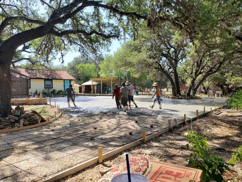 A group of people are working on a concrete driveway.