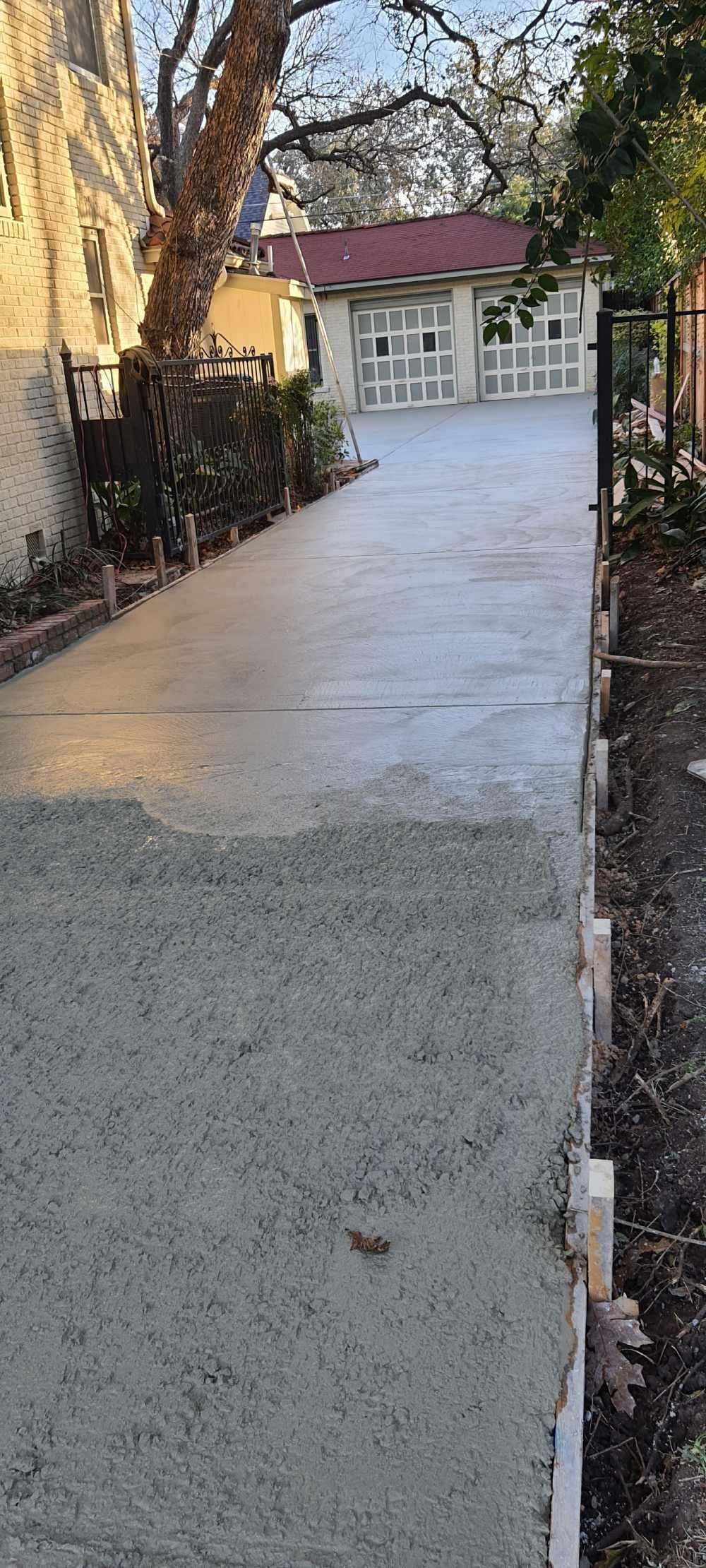 A concrete driveway leading to a house with two garage doors.