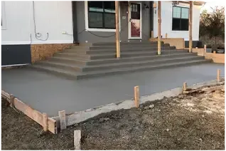 A concrete patio is being built in front of a house.