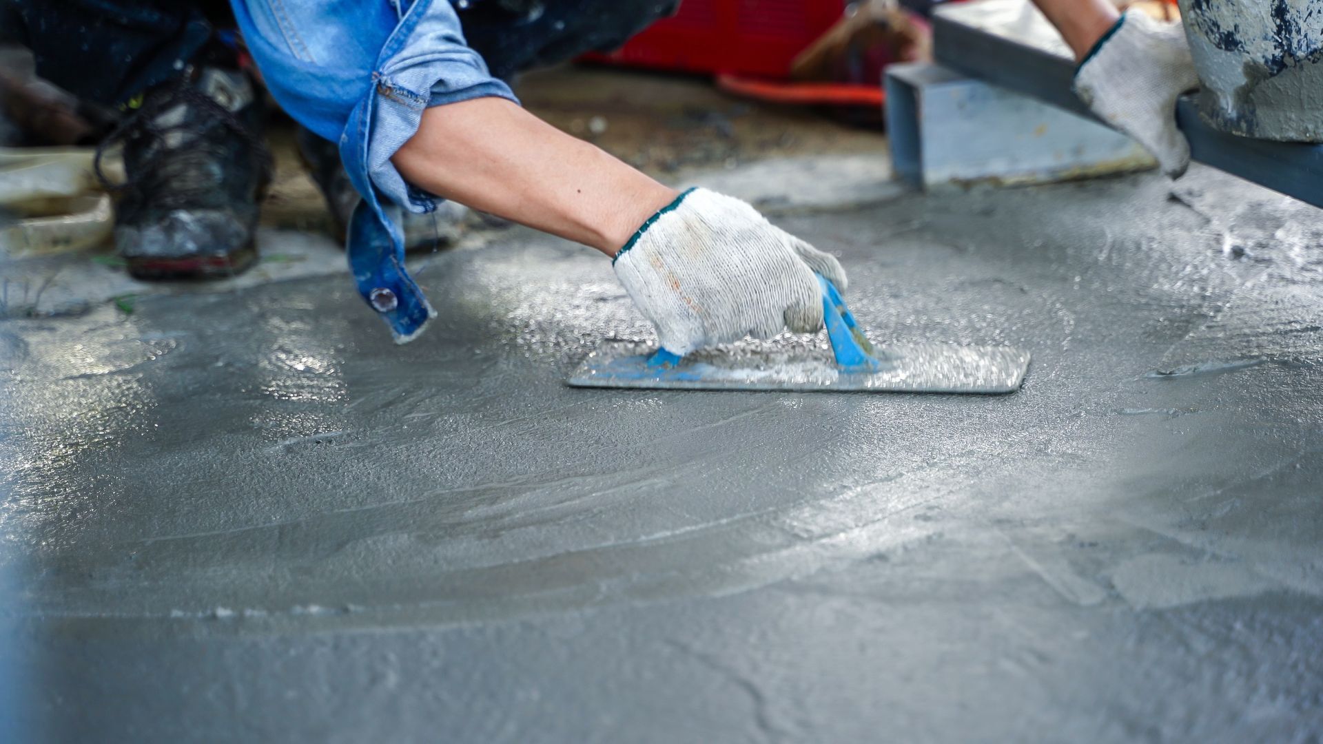 A person is plastering a concrete floor.