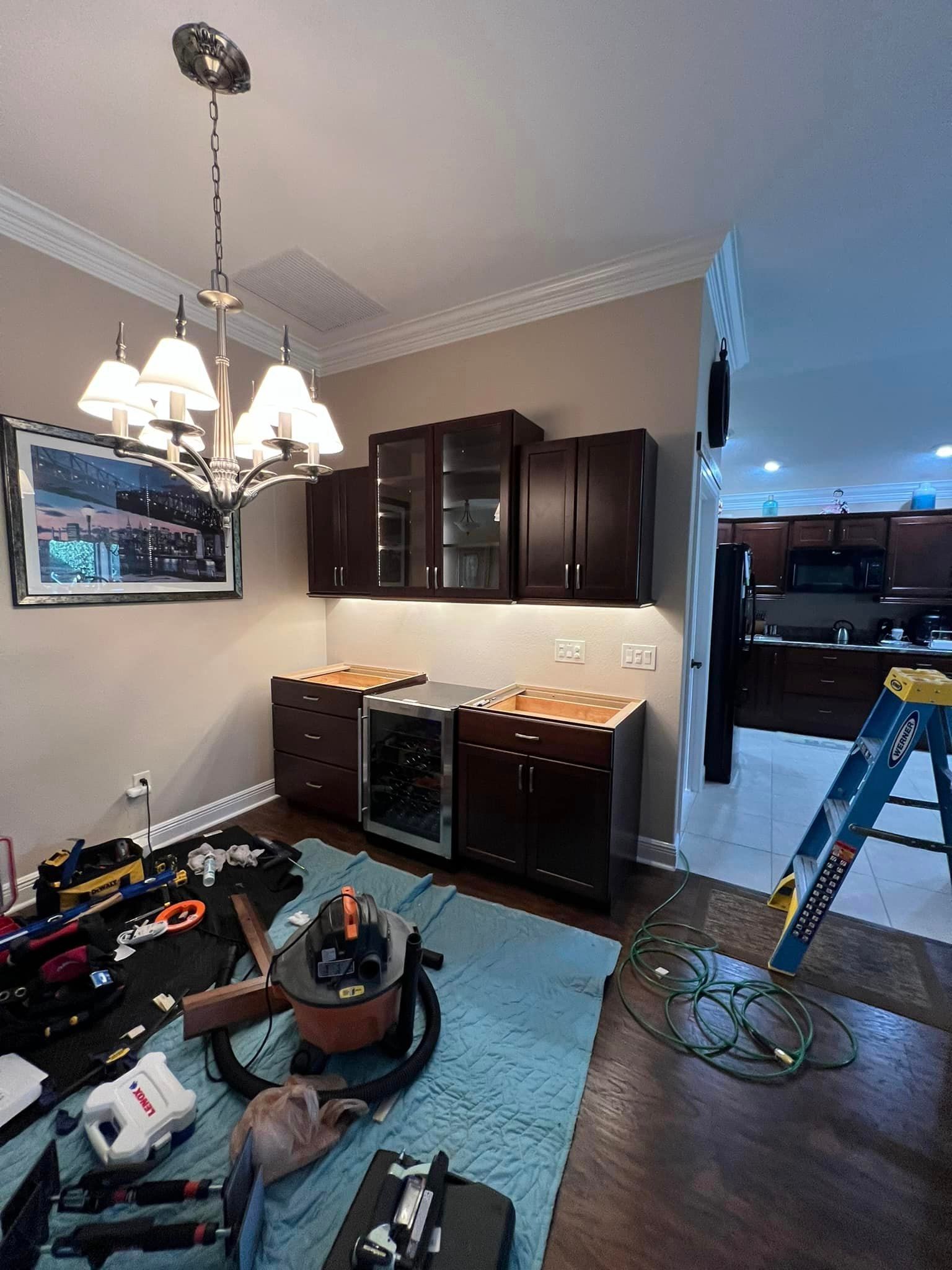 A kitchen is being remodeled with a ladder in the middle of the room.