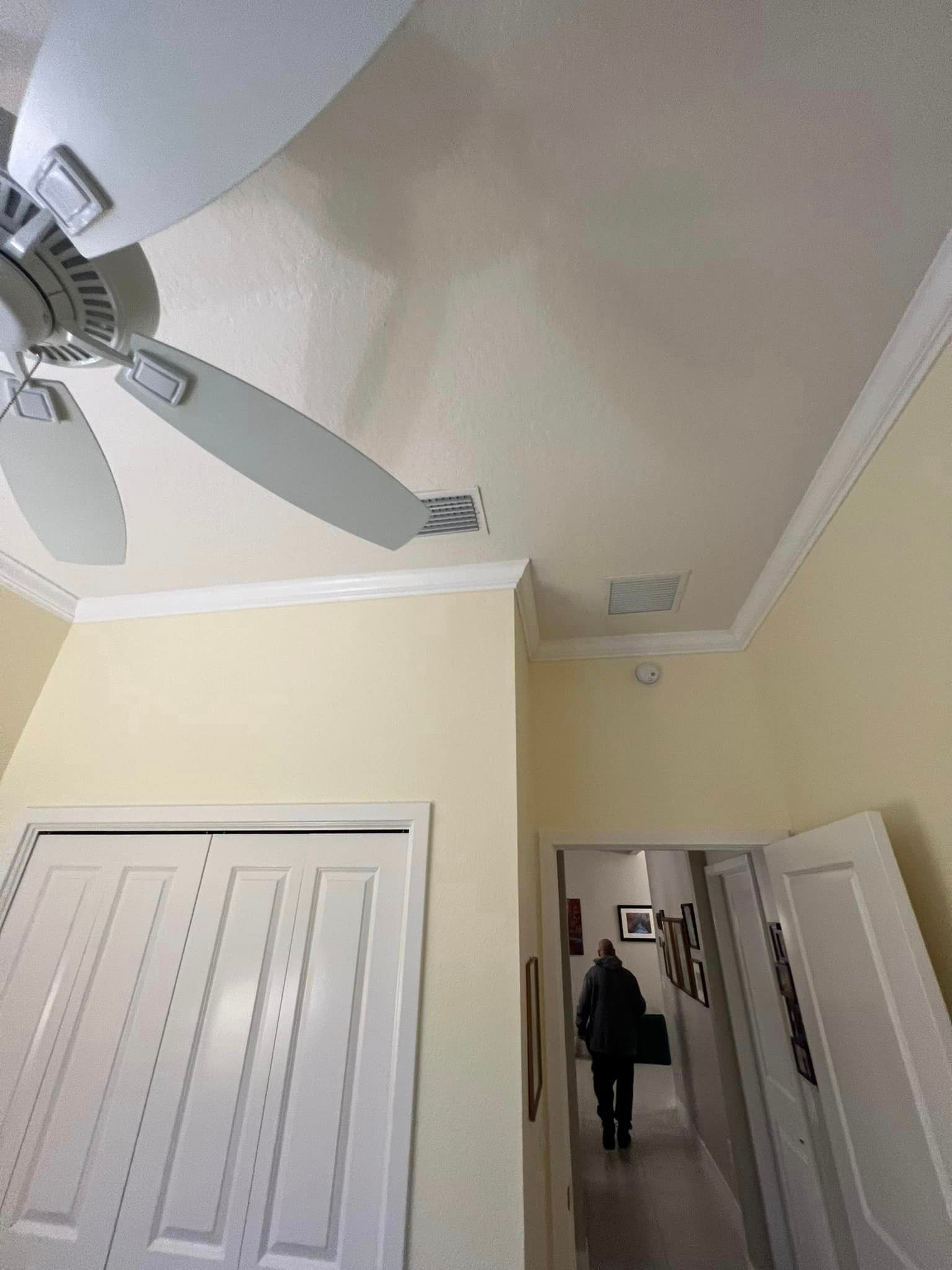 A ceiling fan is hanging from the ceiling of a hallway.