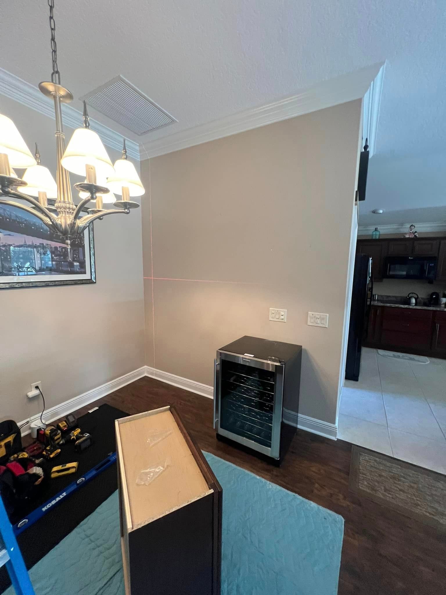 A dining room with a wine cooler and a chandelier.