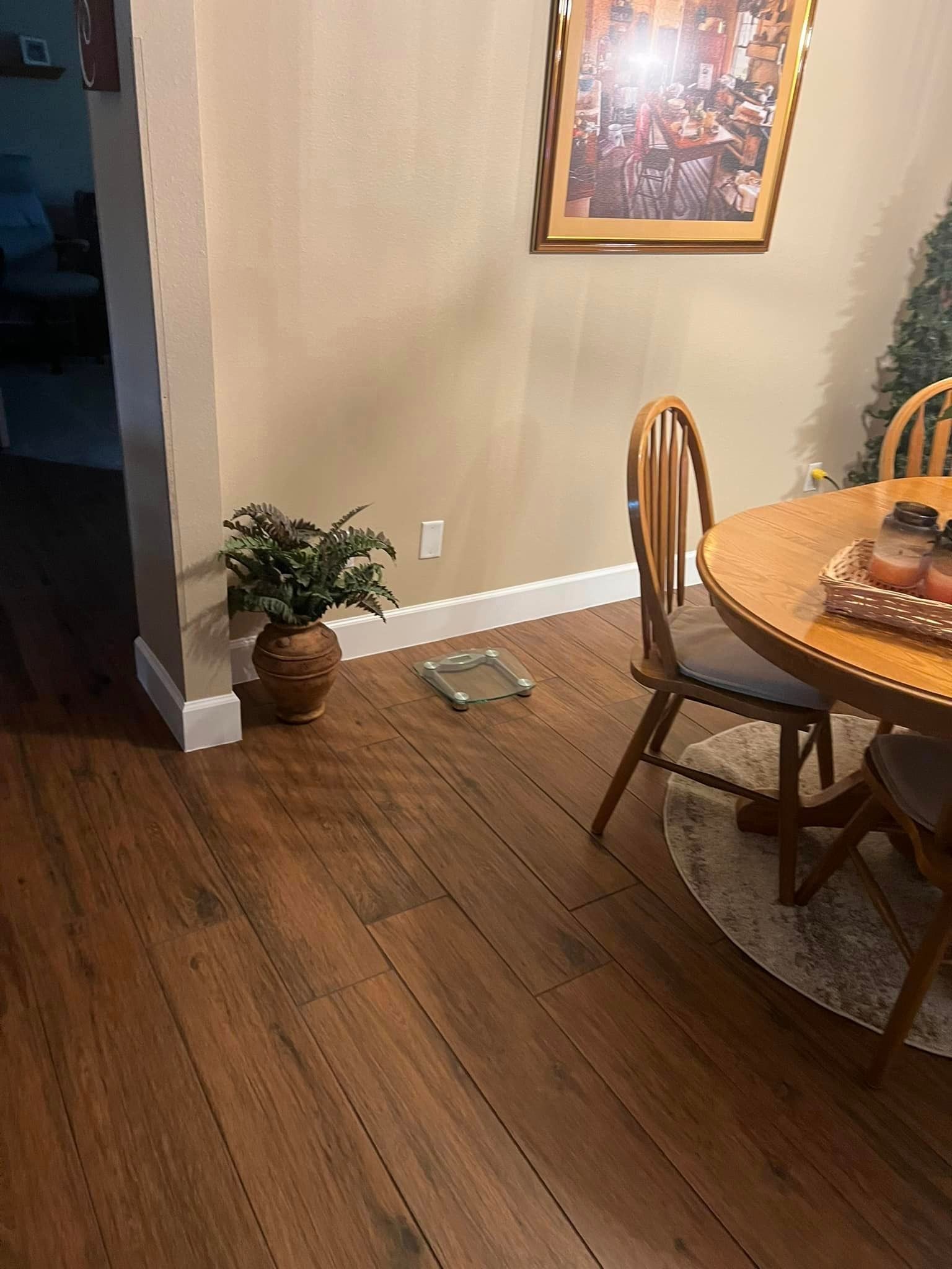 A dining room with a table and chairs and a picture on the wall.